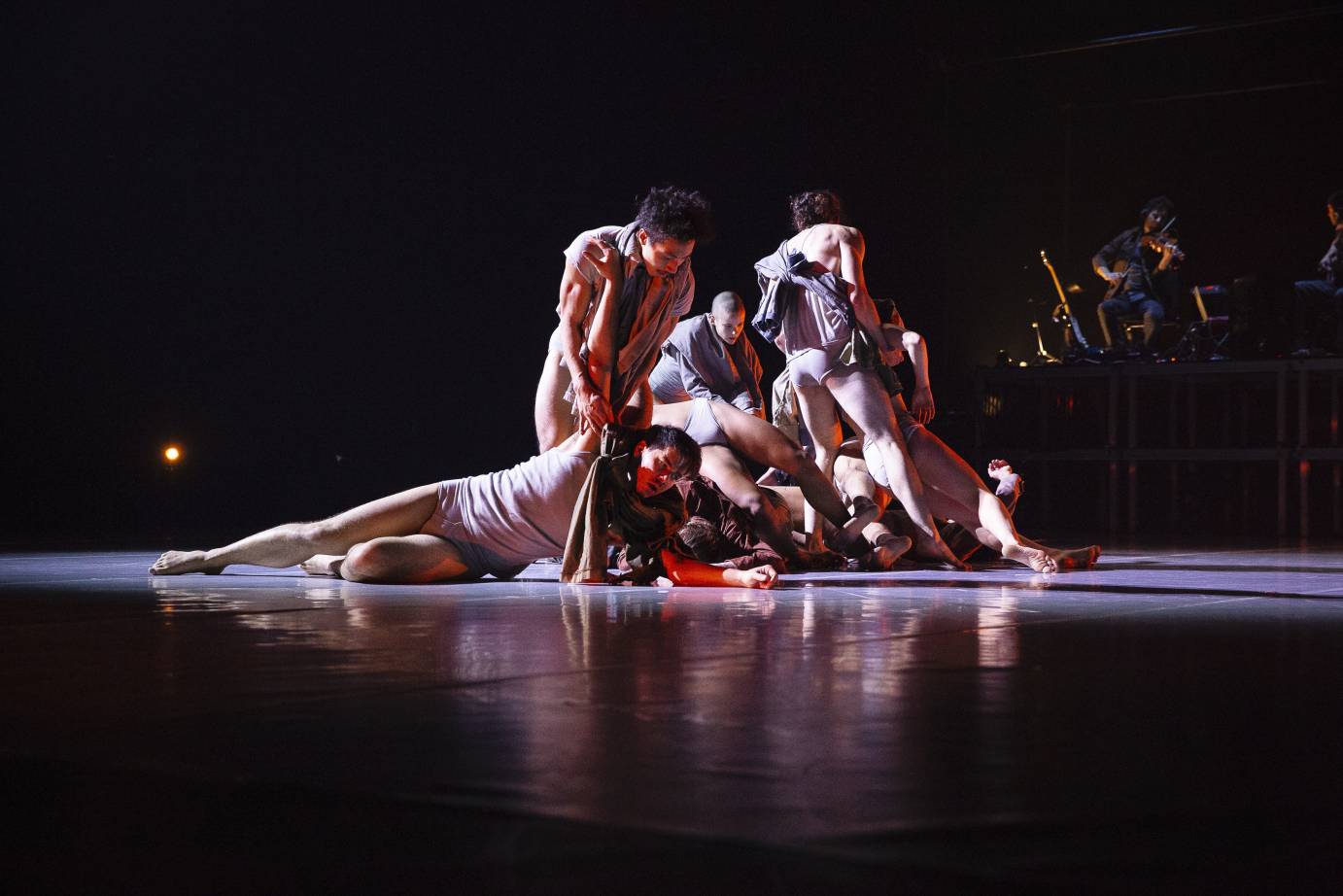 Dancers lie on the stage as two try to help them up